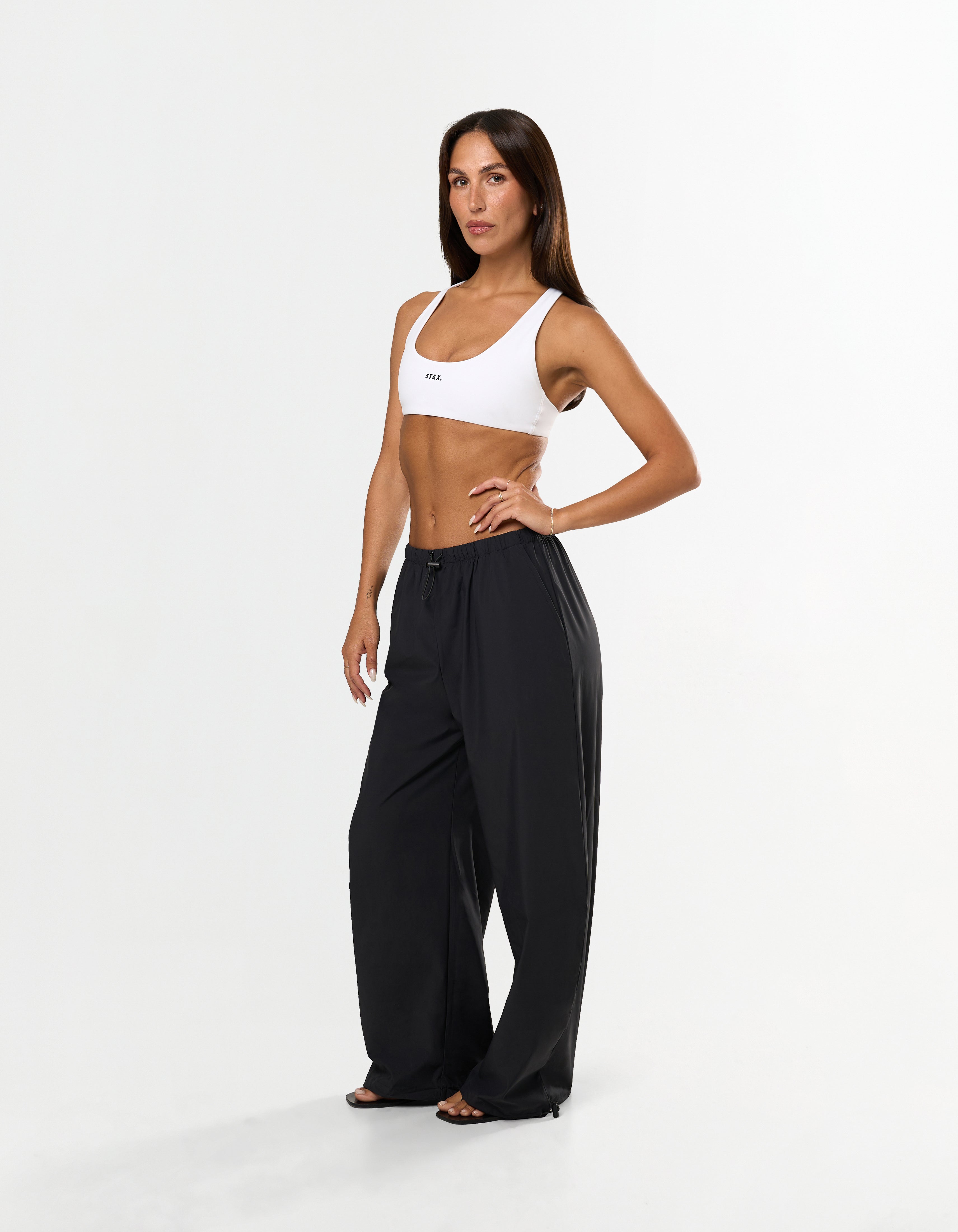 Front view of model wearing STAX. Stella Pants in black with Elastic and toggle drawcord waistband and white STAX. sports bra