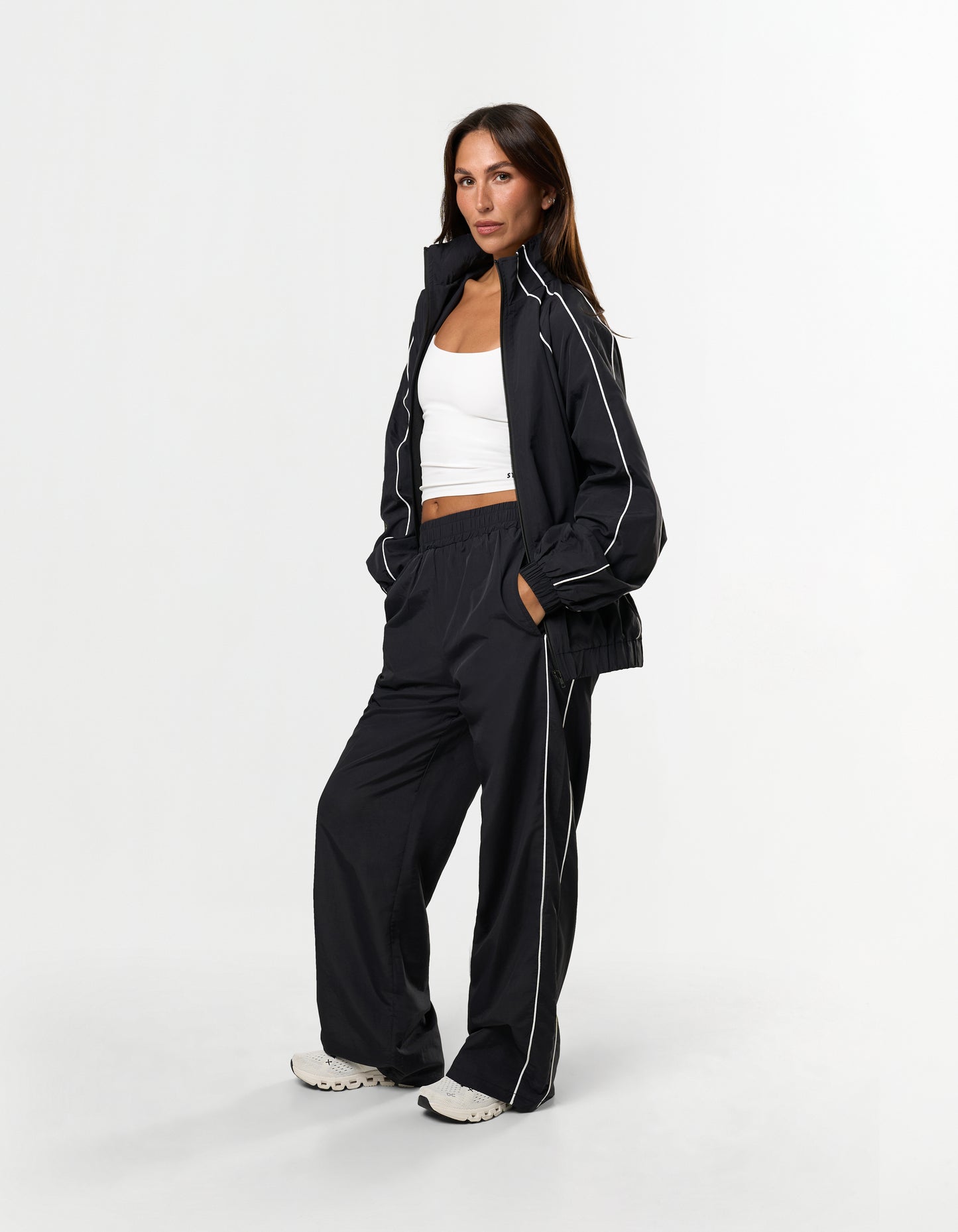 Front view of model wearing STAX. Woven Track Jacket in black with matching Track Pants