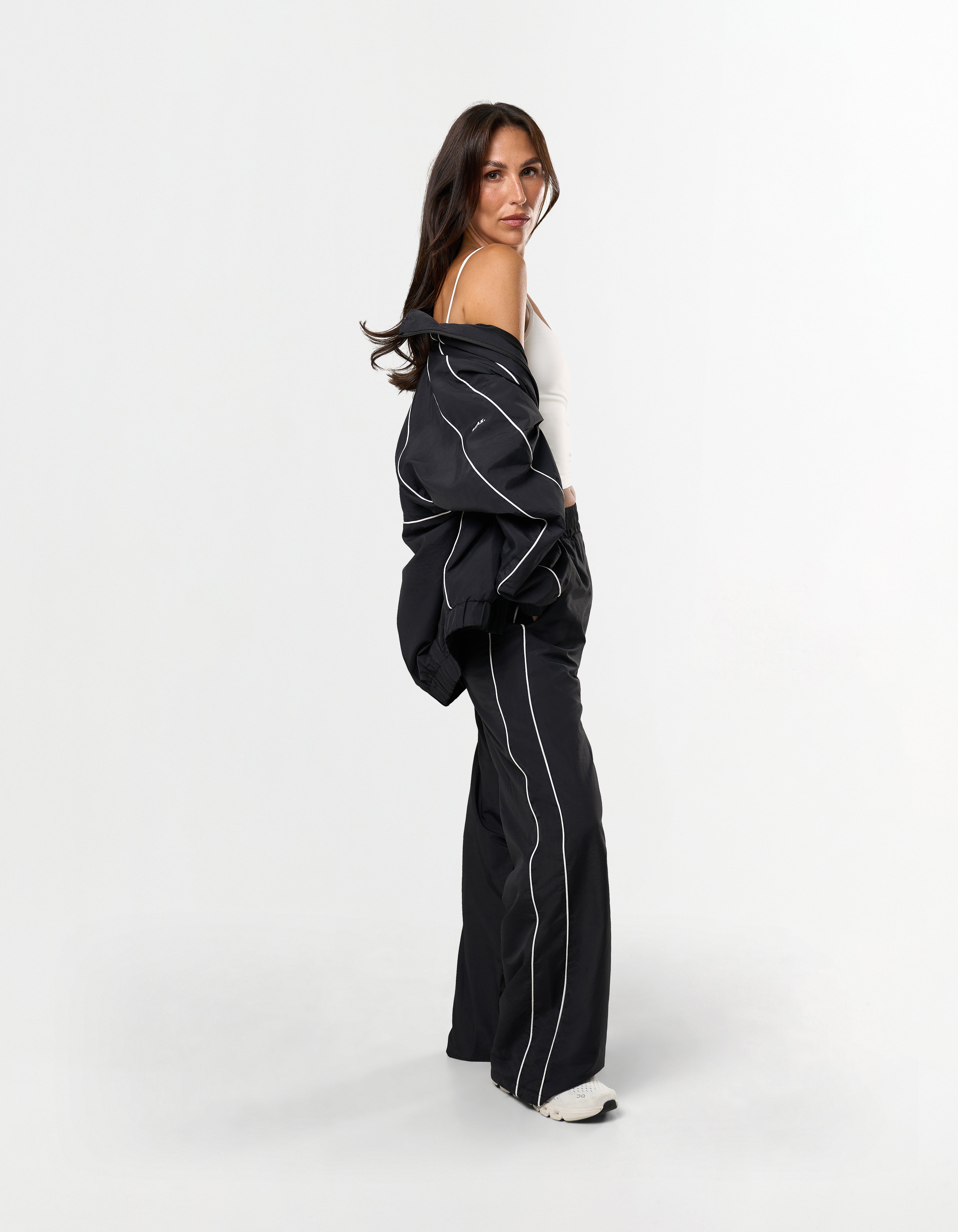 Side profile of STAX. Woven Track Jacket over the shoulder with matching woven track pants 