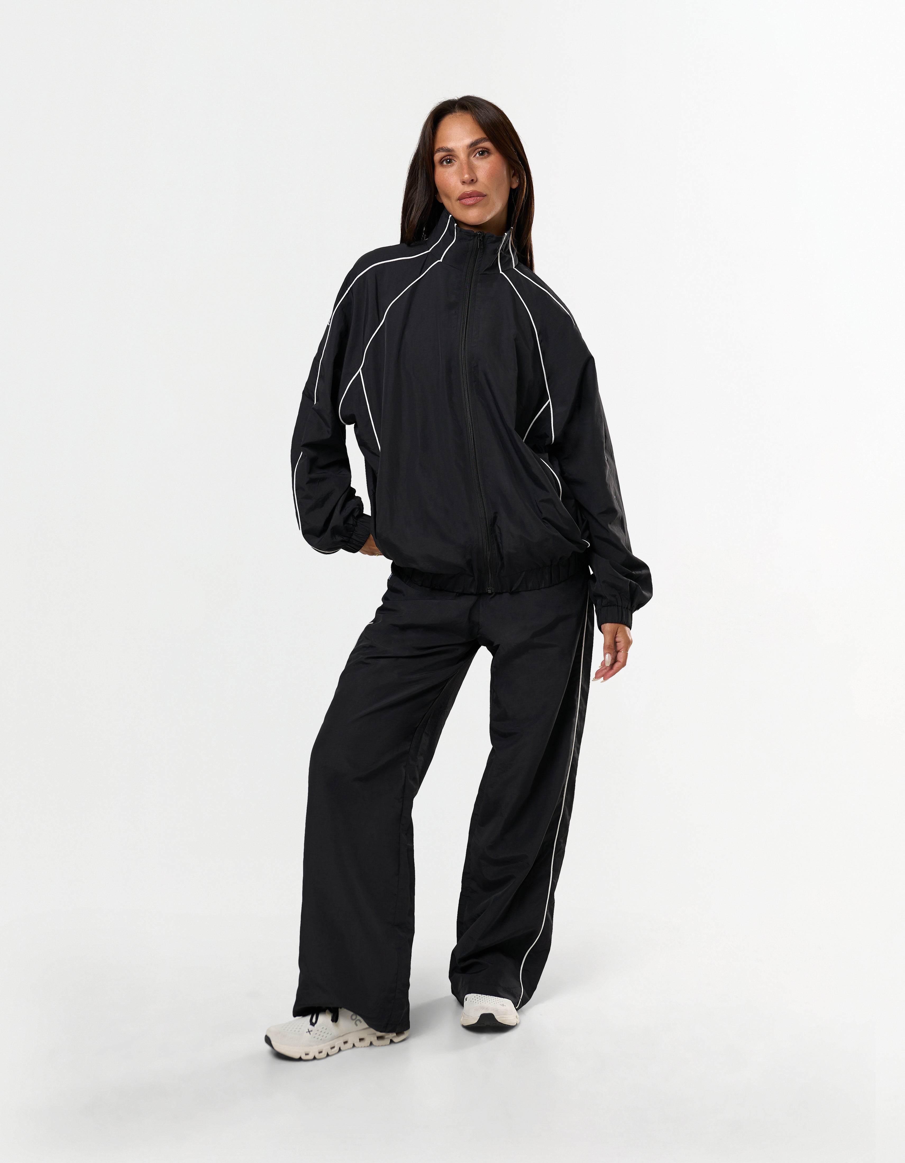 Front view of model wearing STAX. Woven Track Jacket showing off contrast piping detail
