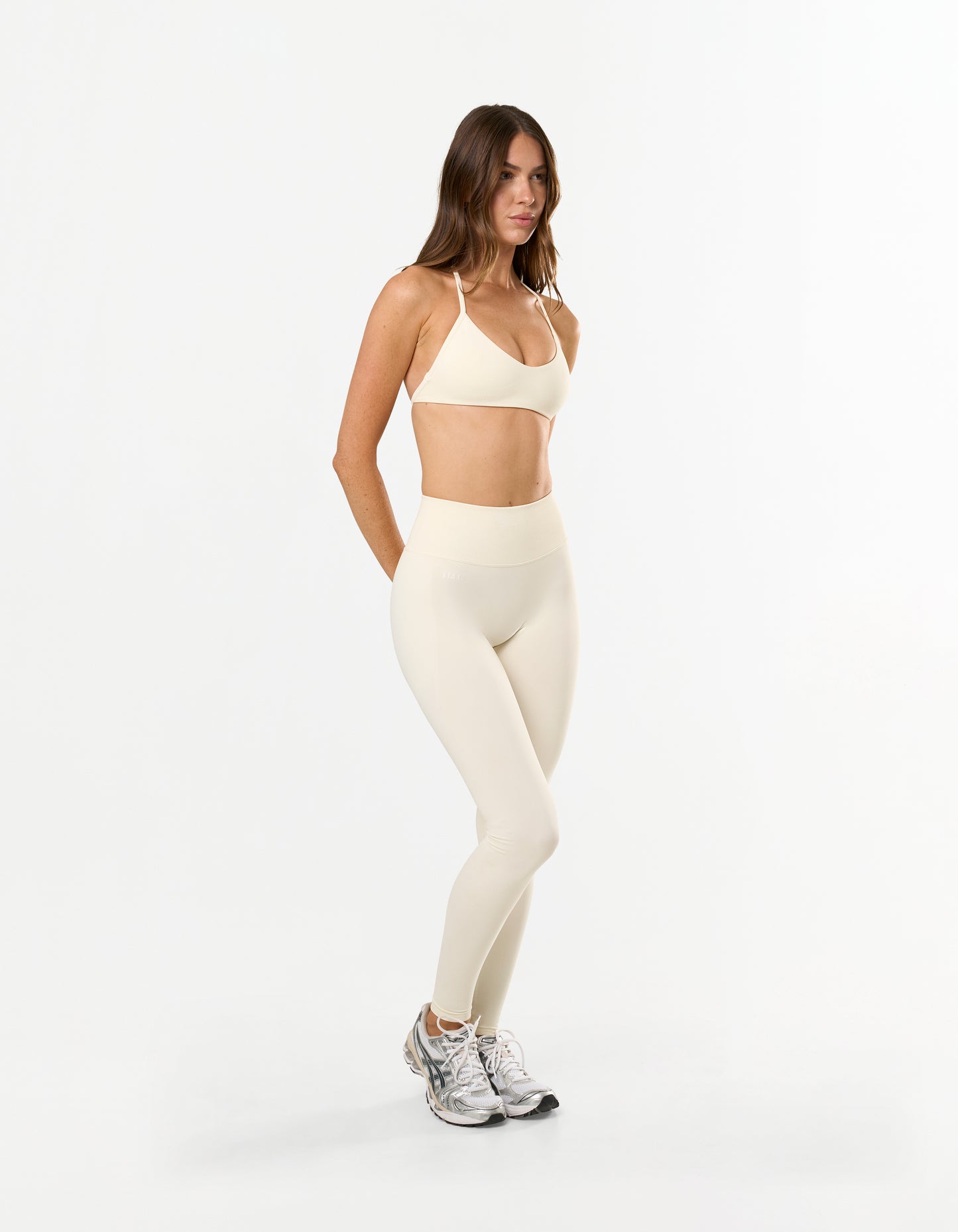 Front view of model wearing STAX. Premium Seamless Skulpt Leggings in Cream showing high waist compressive fit with STAX. silicone logo