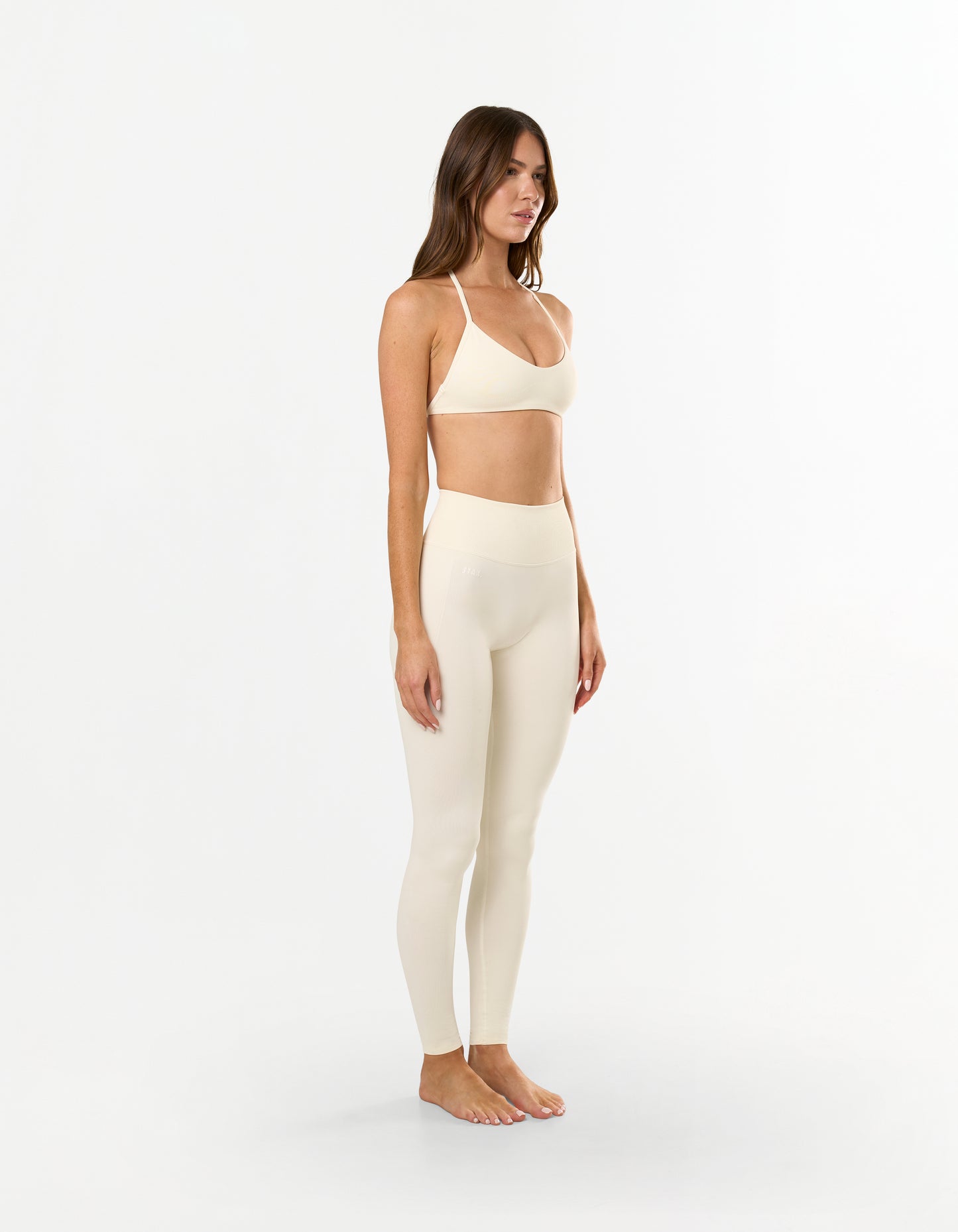 Side profile of model wearing STAX. Premium Seamless Skulpt Leggings in Cream emphasising secure sculpted silhouette 