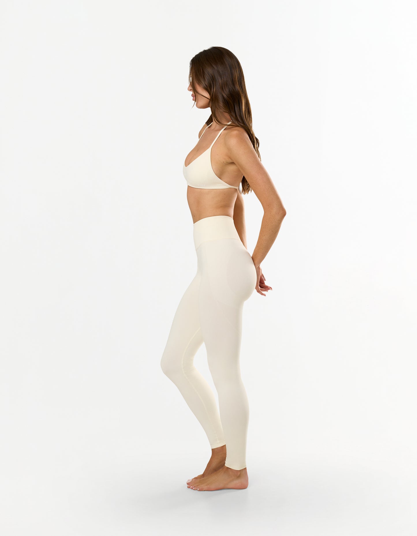Side profile of model wearing STAX. Premium Seamless Skulpt Leggings in Cream delivering a second-skin feel