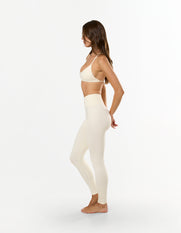Side profile of model wearing STAX. Premium Seamless Skulpt Leggings in Cream delivering a second-skin feel