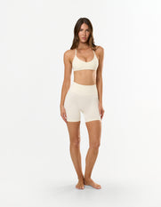 Front view of model wearing STAX. Premium Seamless Skulpt Bralette in Cream with matching skulpt midi bike shorts 