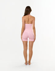 Back view of model wearing STAX. Premium Seamless Skulpt Midi Bike Shorts in Pink showing flattering V back glute contouring seam