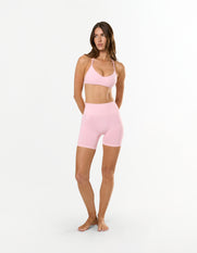 Front profile of model wearing STAX. Premium Seamless Skulpt Midi Bike Shorts in Pink with matching seamless skulpt bralette 