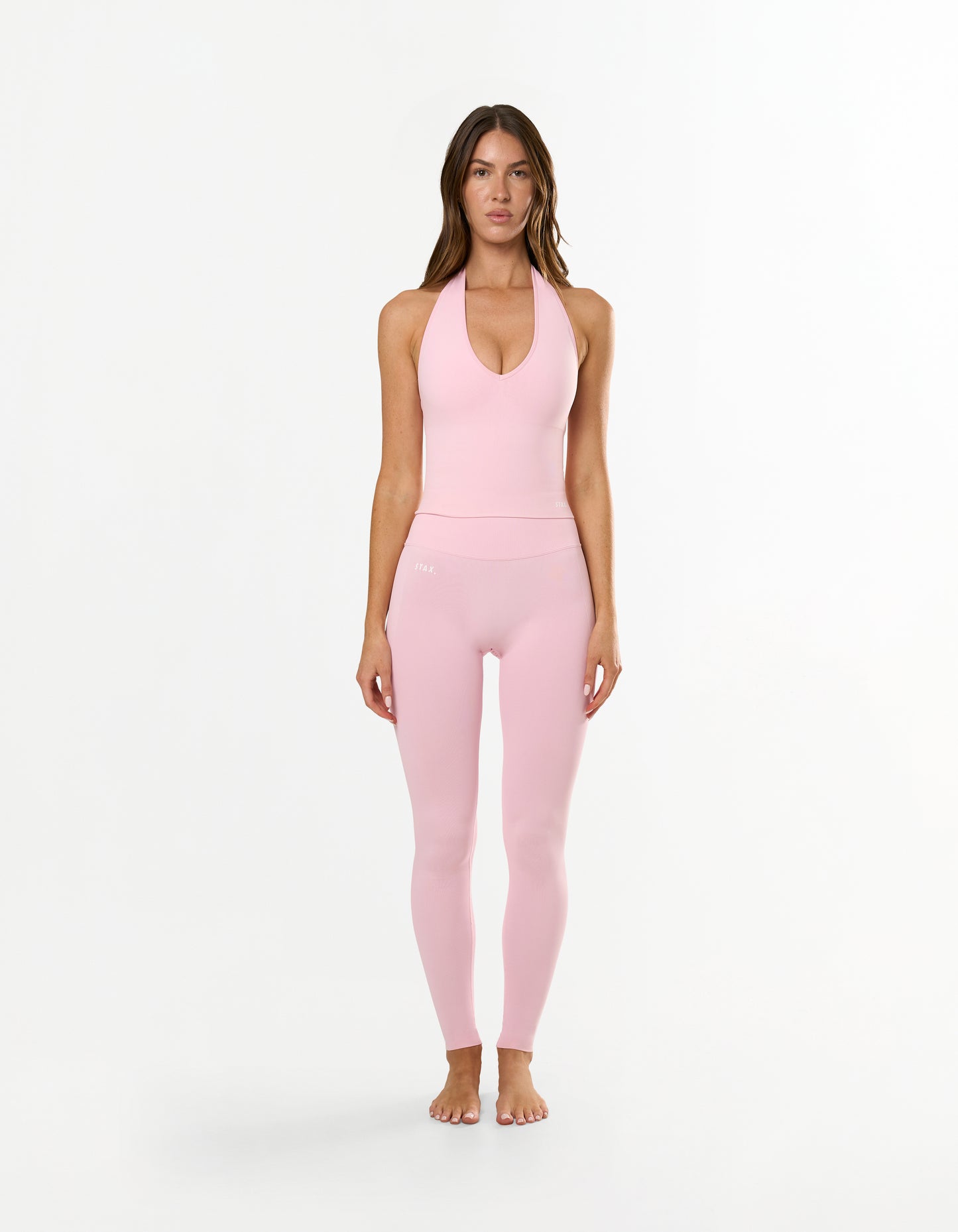 Front view of model wearing STAX. Premium Seamless Skulpt Midi Bike Shorts in Pink made from premium nylon spandex fabric with printed silicone logo 