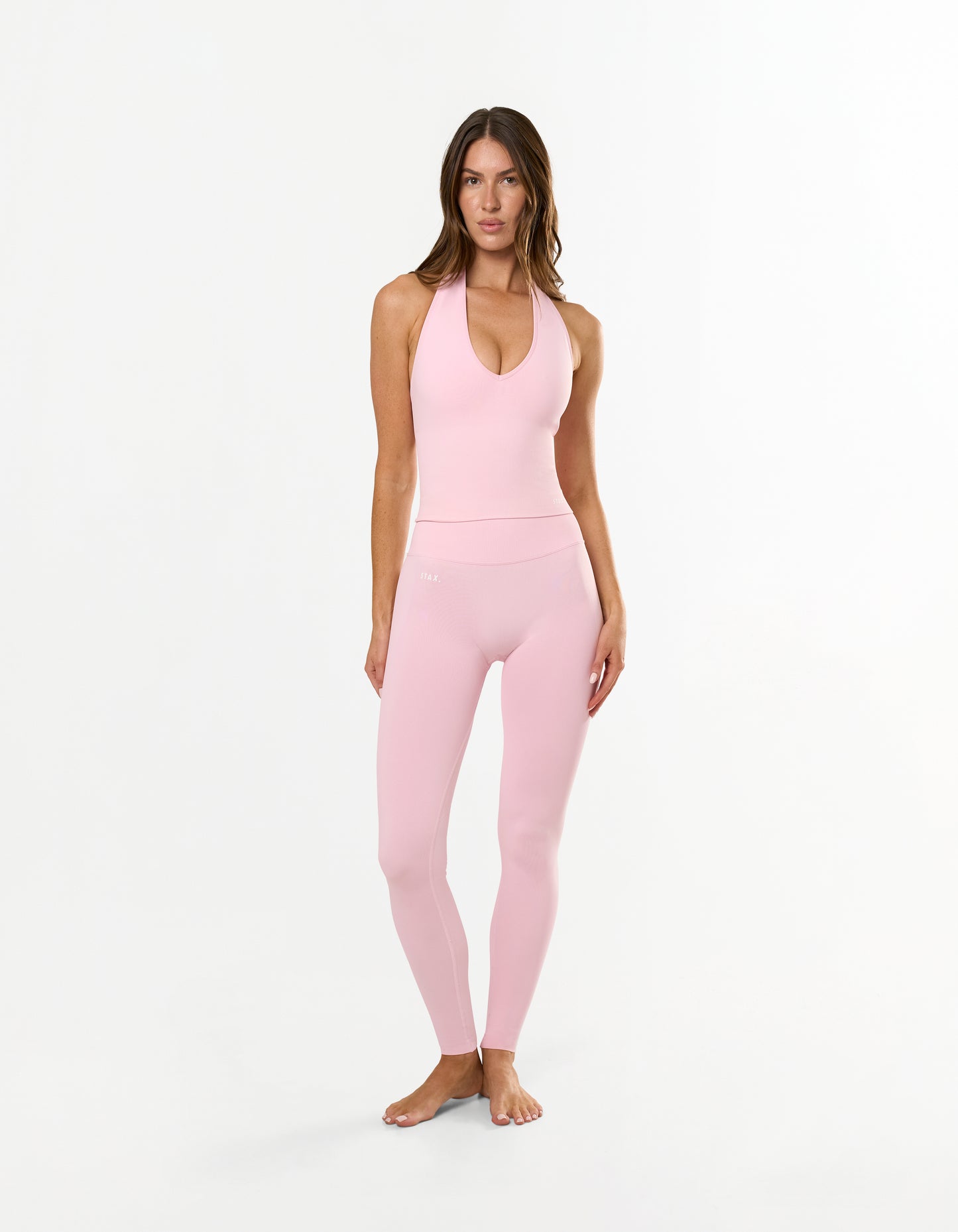 Front view of model wearing STAX. Premium Seamless Skulpt Leggings in Pink with matching skulpt halter tank in pink