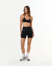 Front view of model wearing STAX. Premium Seamless Skulpt Midi Bike Shorts in Black with matching Skulpt Bralette 