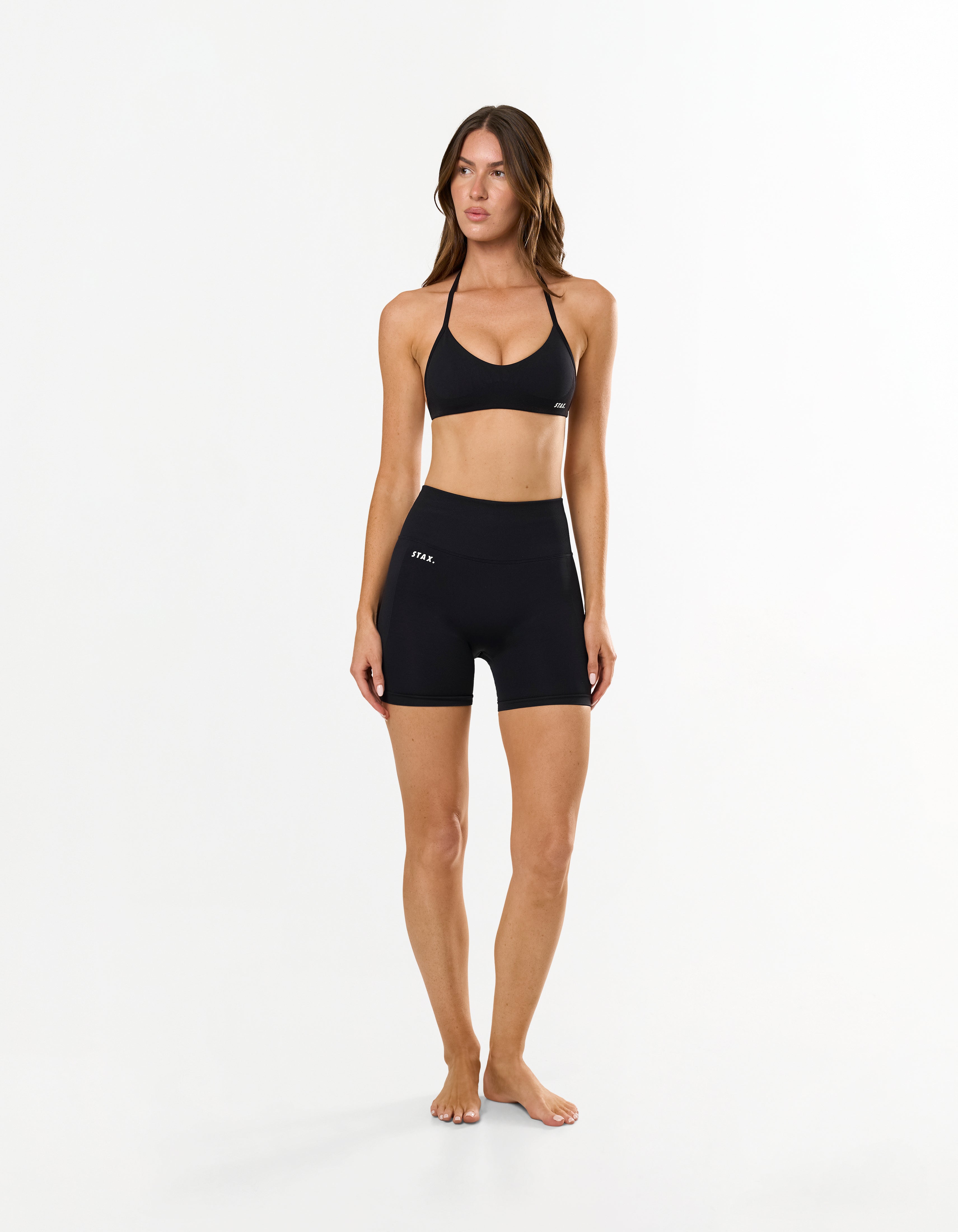 Front view of model wearing STAX. Premium Seamless Skulpt Bralette in Black with matching bike shorts 