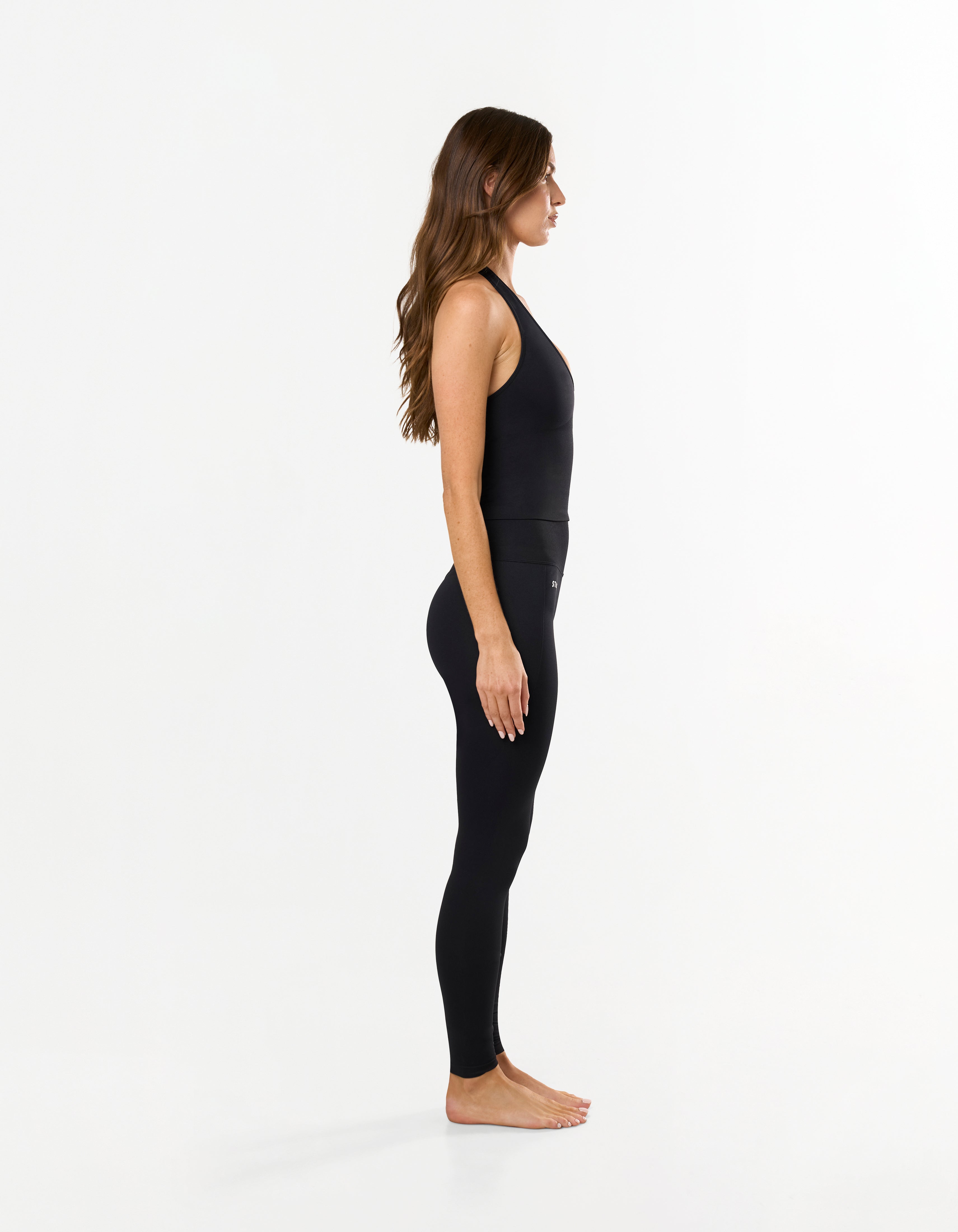 Side view of model wearing STAX. Premium Seamless Skulpt Tights in Black with matching Skulpt halter tank in black