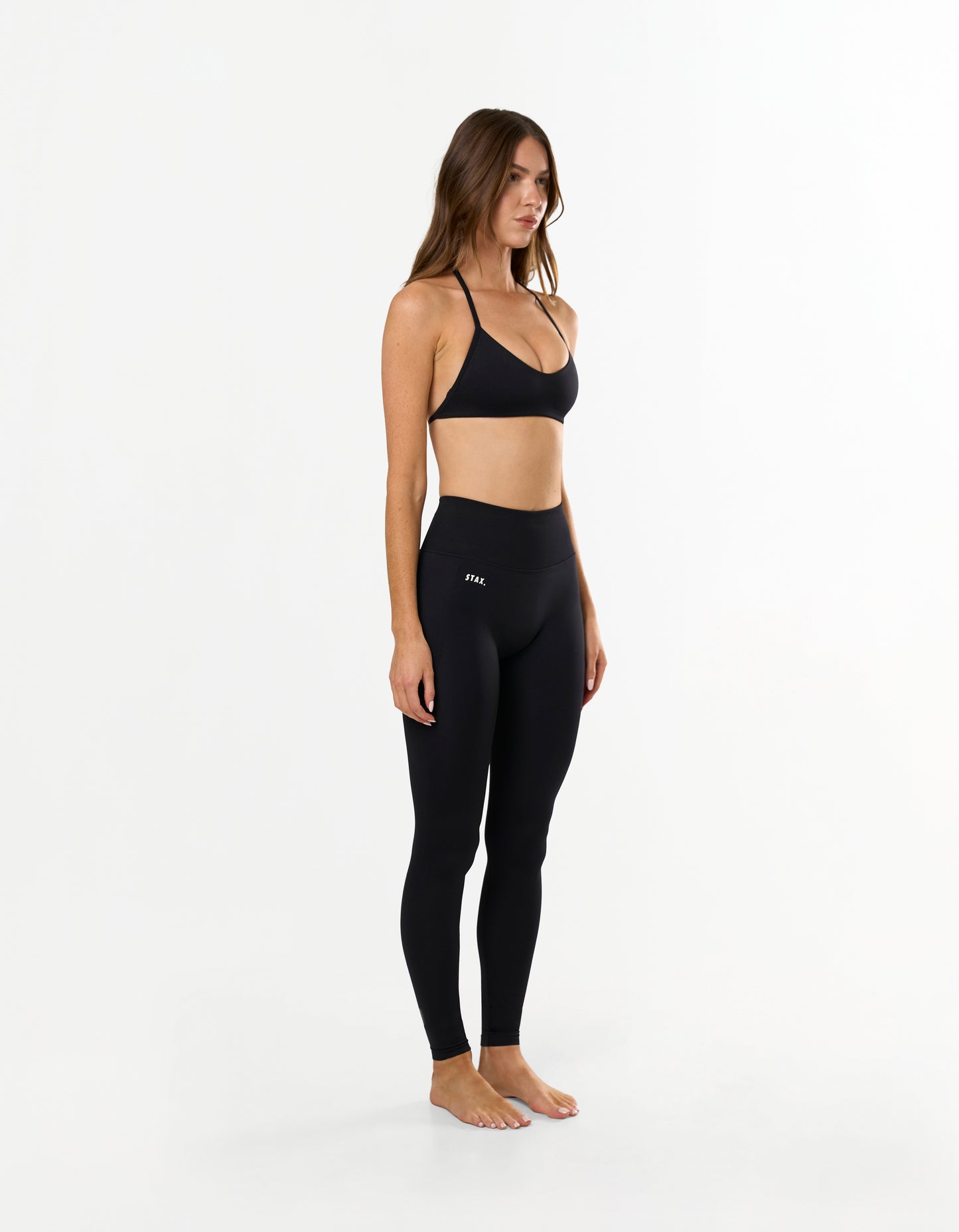 Side view of model wearing STAX. Premium Seamless Skulpt Bralette in Black with matching Premium Seamless Skulpt Full Length Tights