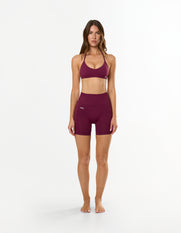 Front profile of model wearing STAX. Premium Seamless Skulpt Midi Bike Shorts  in Burgundy showing flattering compressive fit