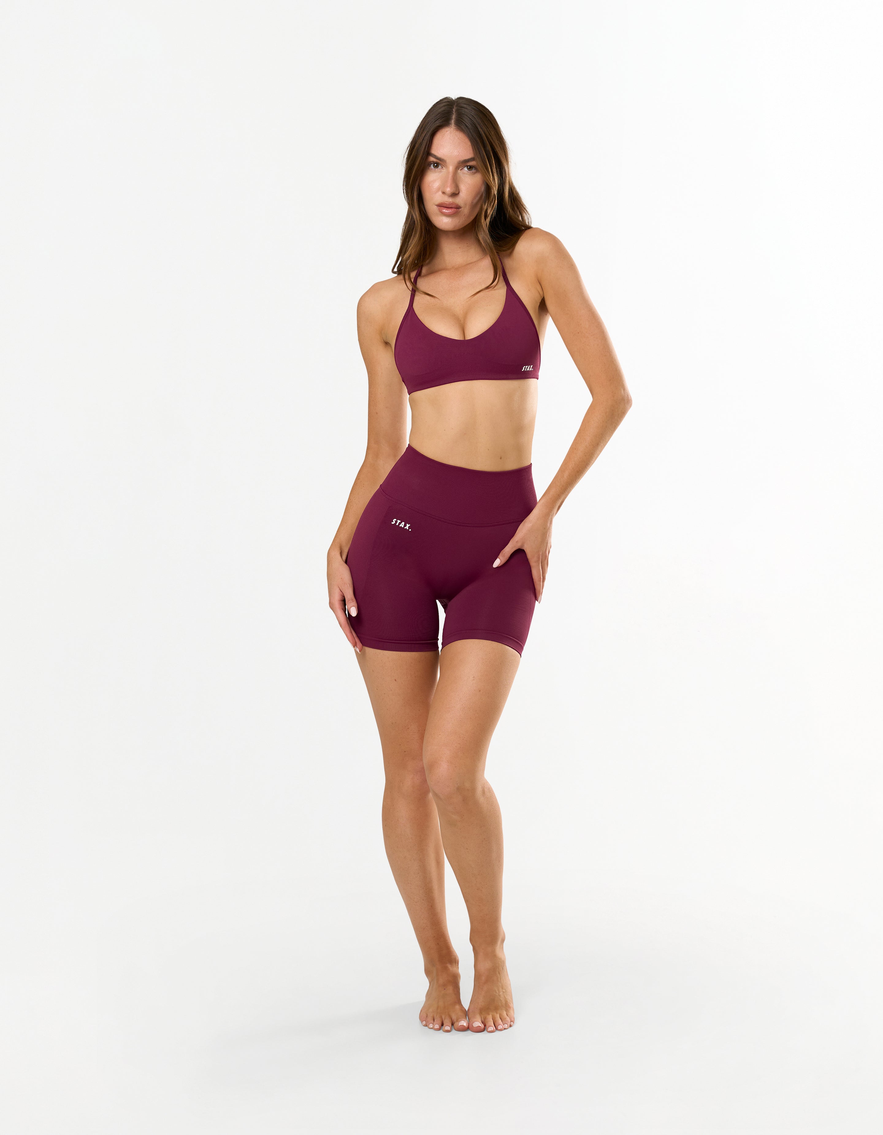 Front view of model wearing STAX. Premium Seamless Skulpt Midi Bike Shorts in Burgundy with matching Burgundy Skulpt Bralette 