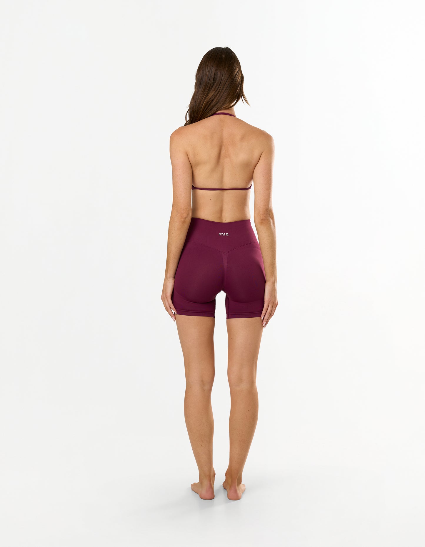 Back view of model wearing STAX. Premium Seamless Skulpt Midi Bike Shorts   in Burgundy showing flattering invisible scrunch detail  
