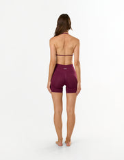 Back view of model wearing STAX. Premium Seamless Skulpt Midi Bike Shorts   in Burgundy showing flattering invisible scrunch detail  