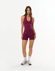 Front view of model wearing STAX. Premium Seamless Skulpt Midi Bike Shorts  in Burgundy showing premium nylon spandex fabric with printed silicone logo 