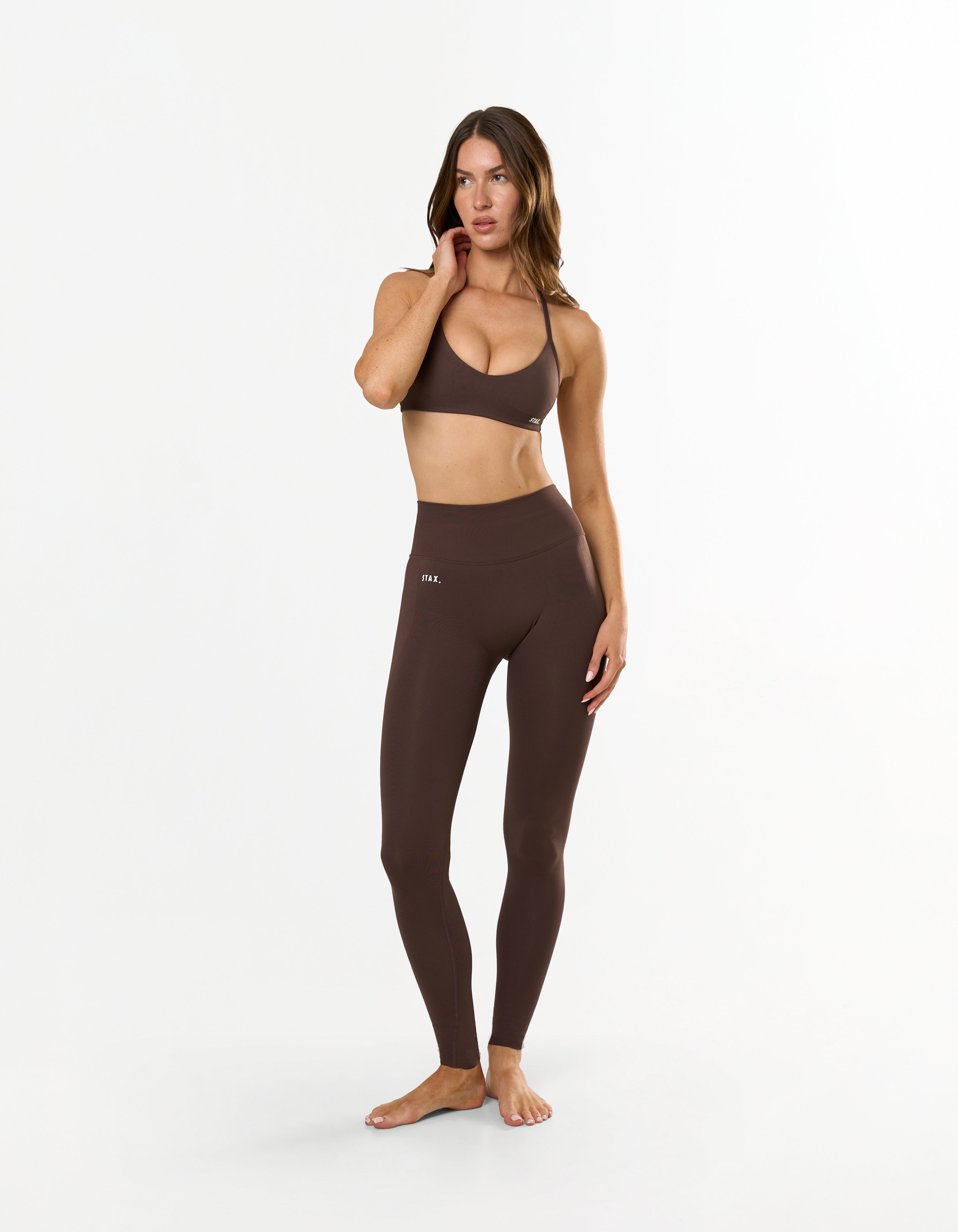 Front view of model wearing STAX. Premium Seamless Skulpt Leggings in Brown with matching skulpt bralette in brown