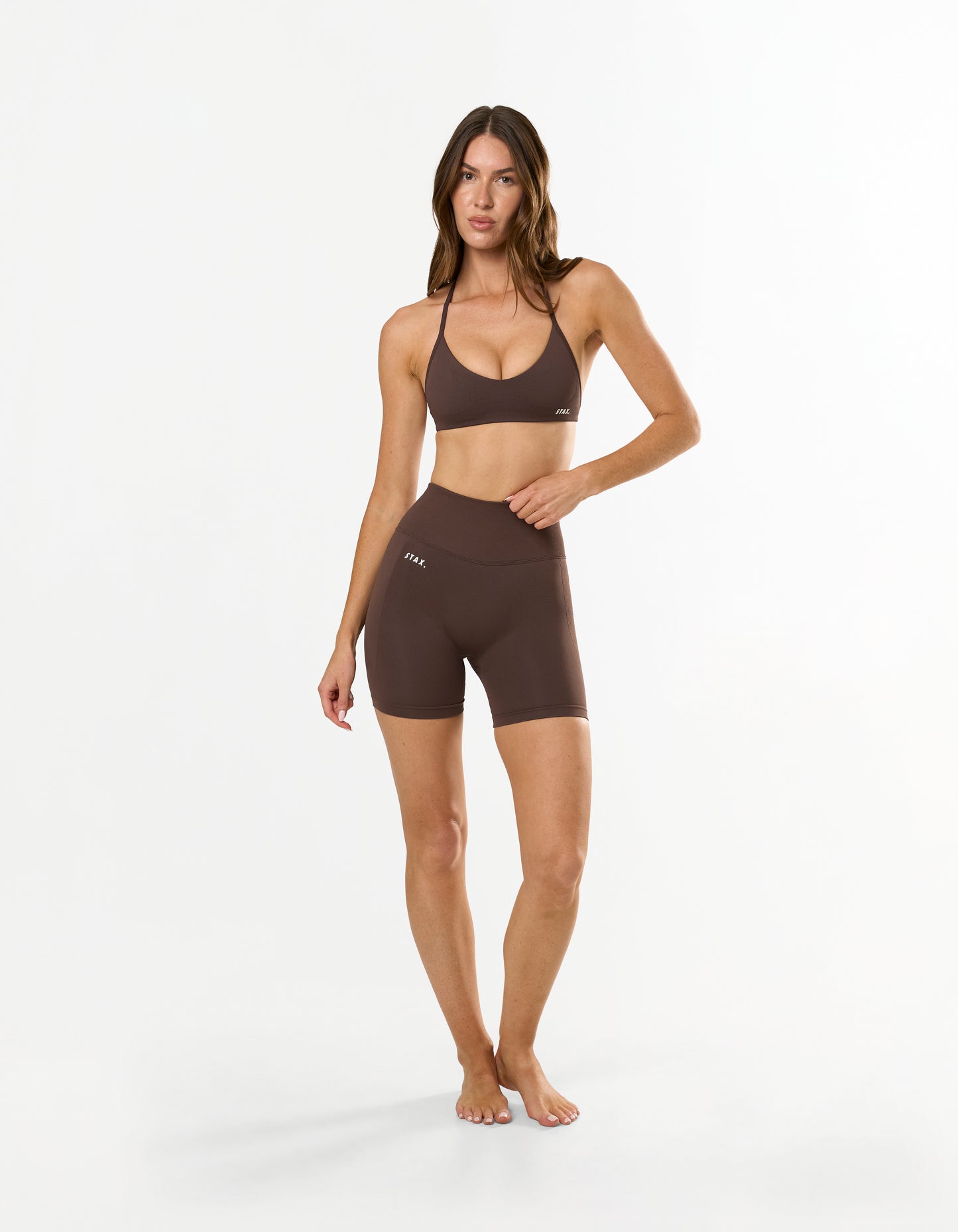 Front view of model wearing STAX. Premium Seamless Skulpt Midi Bike Shorts in Brown with printed STAX. silicone logo