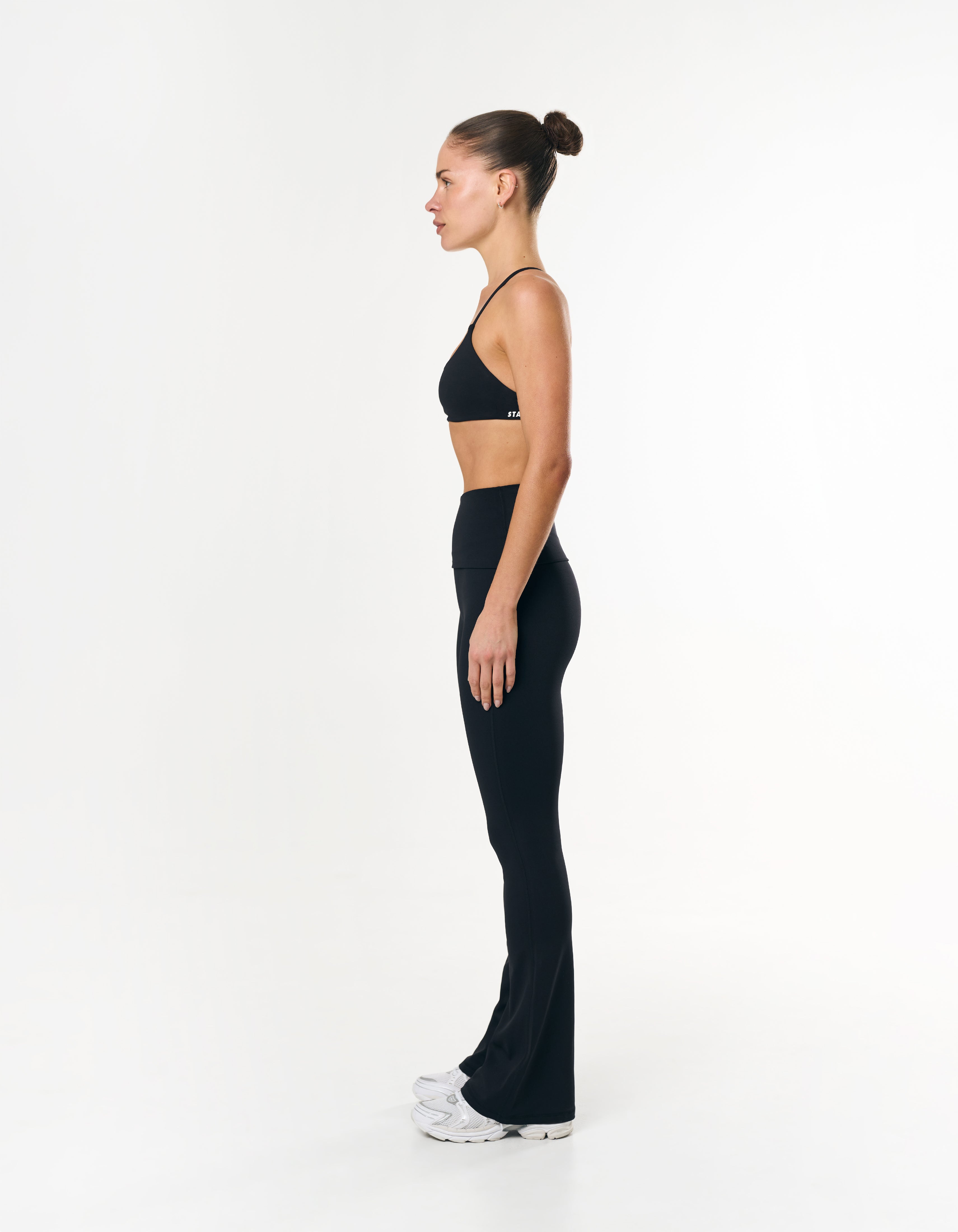 Side profile of STAX. Fold Over Flares in Black showing flattering fit and wide flare hem