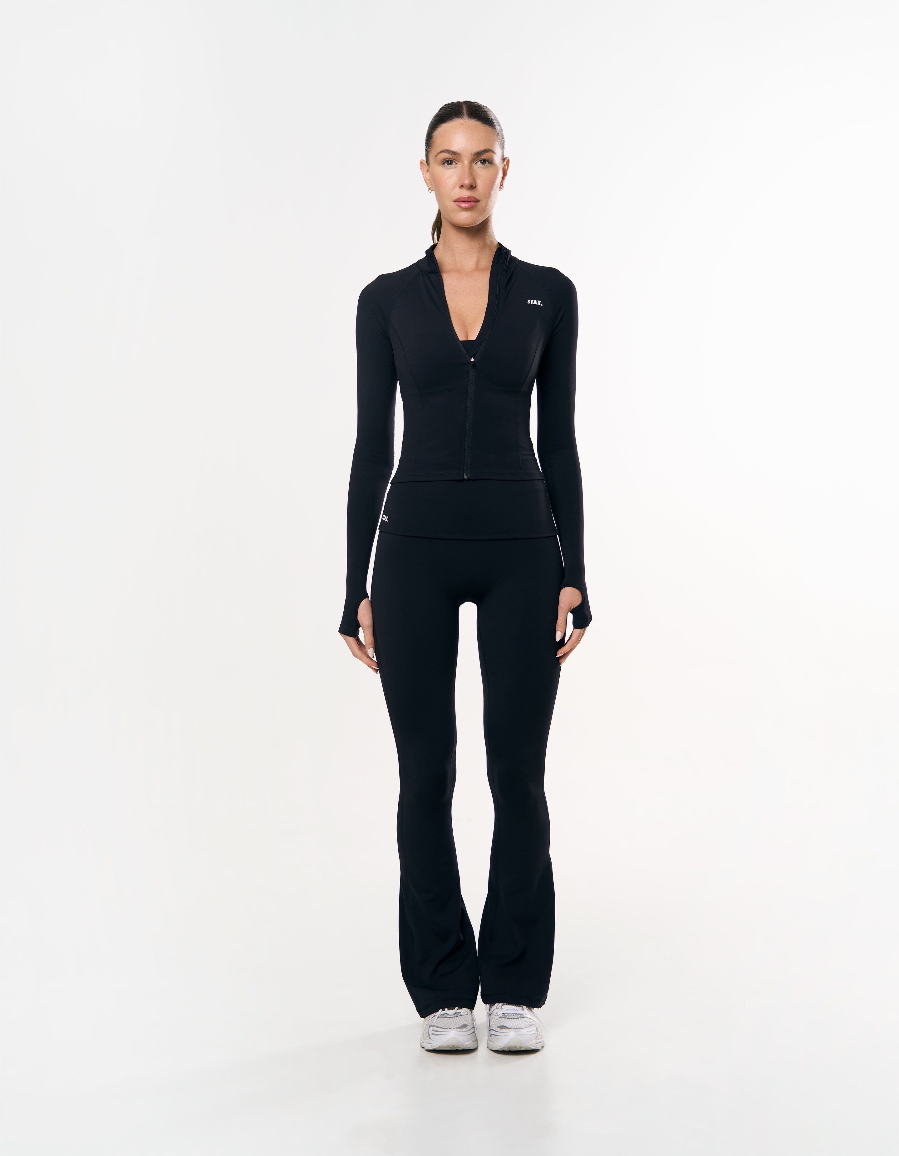 Front view of model wearing STAX. Active Zip Jacket Airlyte in Black with matching black flare tights