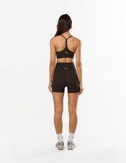 Back view of model wearing STAX. Strappy Crop NANDEX™ in Espresso with matching bike shorts showing flattering fit and small white logos