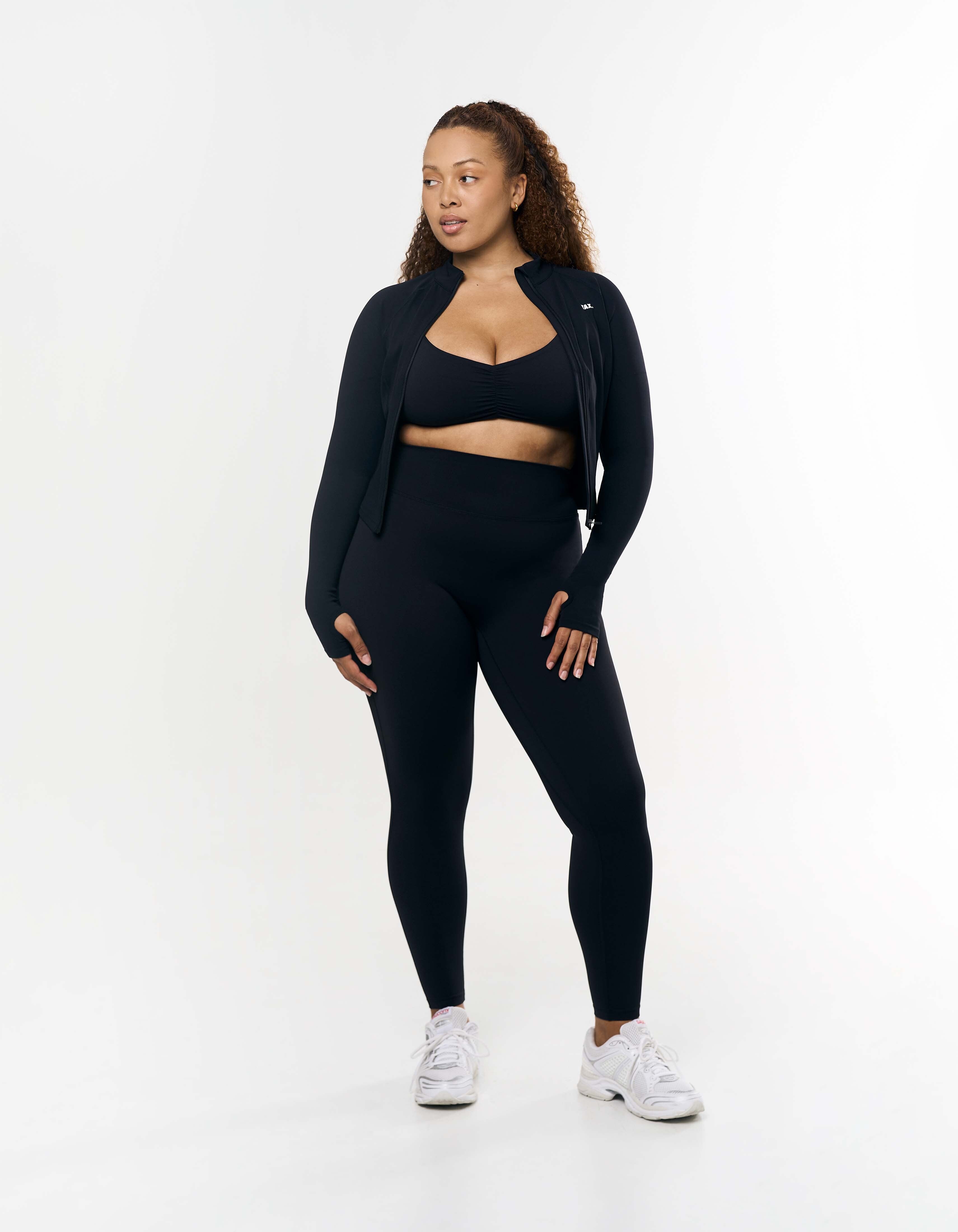 Front view of model wearing STAX. Active Zip Jacket Airlyte in Black with matching Sports bra and tights