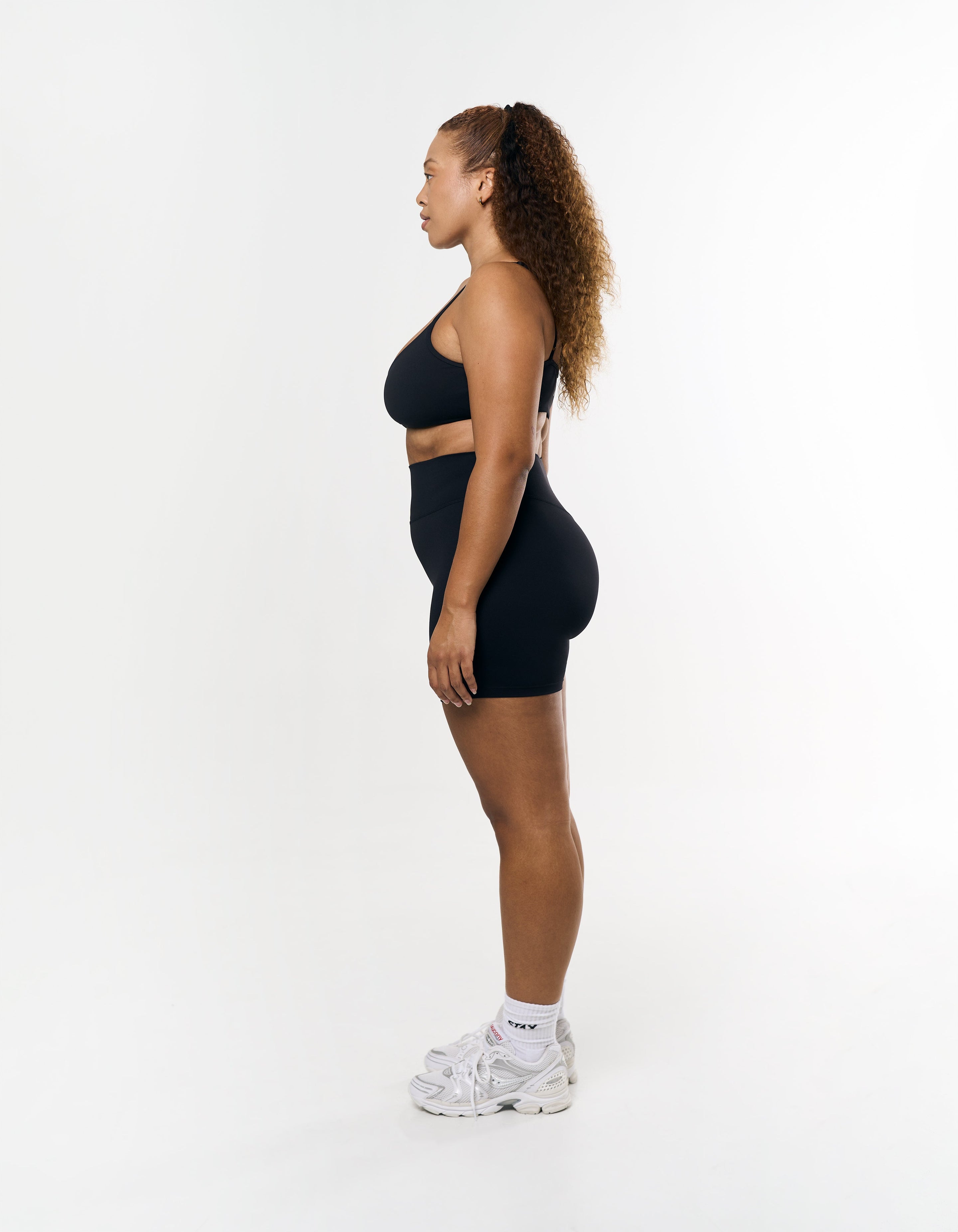 Side profile of STAX. Midi Bike Shorts Airlyte in Black showing flattering tight fit